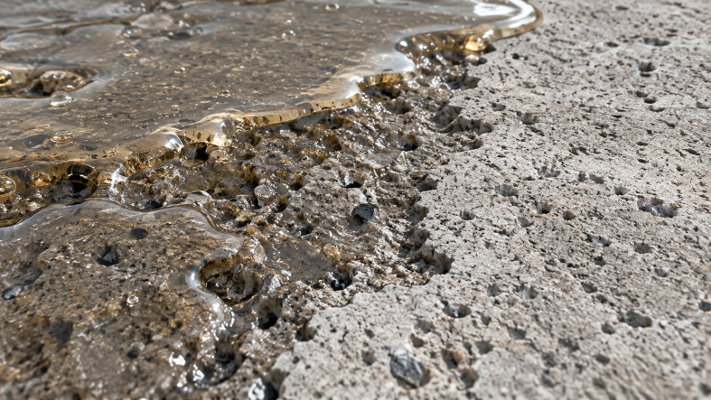 Close-up of liquid epoxy resin penetrating a porous concrete surface, demonstrating strong adhesion and surface bonding in construction applications.